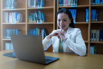 Fototapeta premium University teacher giving online consulting student via laptop in library