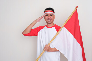 Indonesian man doing salute when holding country flag with happy expression