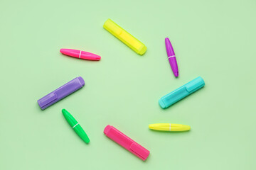 Frame made of colorful markers on green background