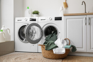 Modern washing machines with dirty clothes in laundry room