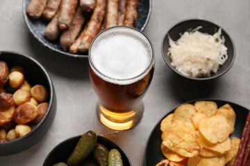 Glass of cold beer and different snacks on grey background. Oktoberfest celebration
