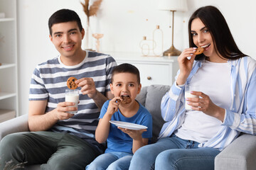 Happy family eating cookies with milk at home