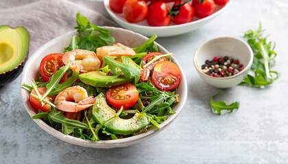 Fresh summer salad with shrimp, avocado and tomato cherry in bowl on light table. Concept of healthy eating.