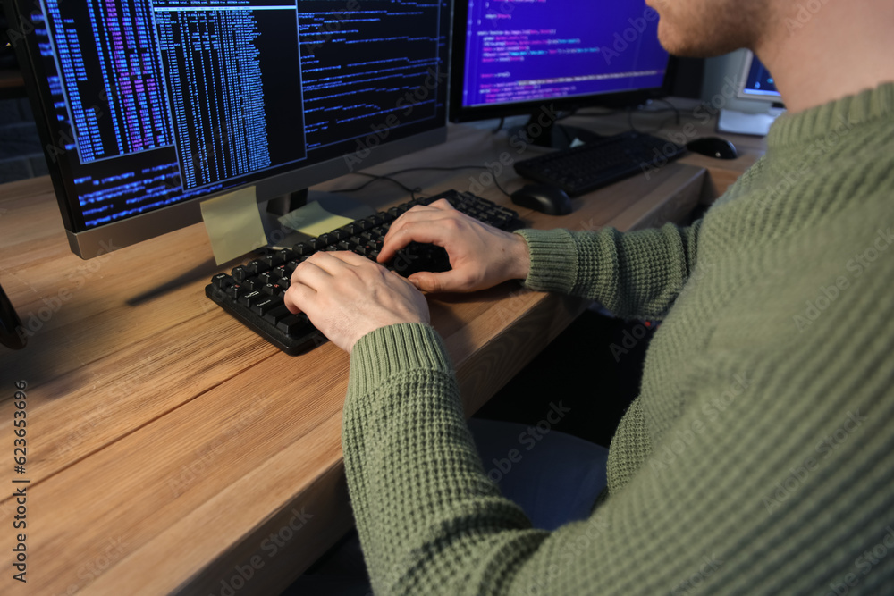 Poster male programmer working with computer in office at night, closeup