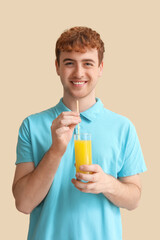 Fototapeta premium Young man with glass of orange juice on beige background