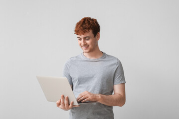 Male programmer working with laptop on light background