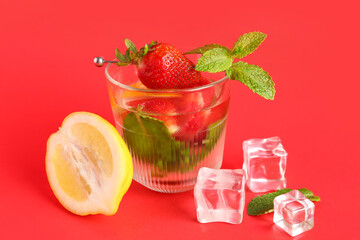 Glass of fresh lemonade with strawberry and lemon on red background