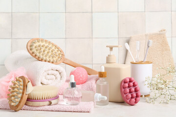 Fototapeta na wymiar Composition with different bath supplies and cosmetic products on table near light tile wall