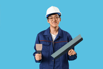 Asian decorator with putty knives on blue background
