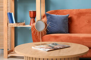 Interior of living room with orange sofa and mirror on wooden coffee table