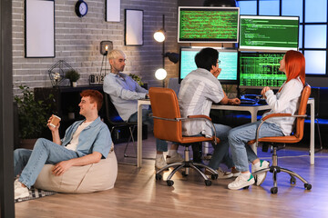 Team of young programmers working in office at night