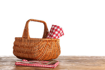 Wicker picnic basket with napkin and cutlery on wooden table against white background