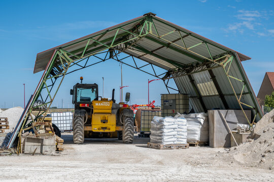 engin de chantier de la marque manitou sous un auvent entour&eacute; de mat&eacute;riel