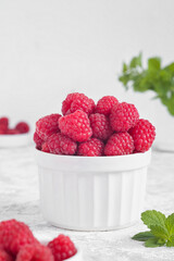 Bowl with fresh organic raspberry and green mint on a white background. Copy space.