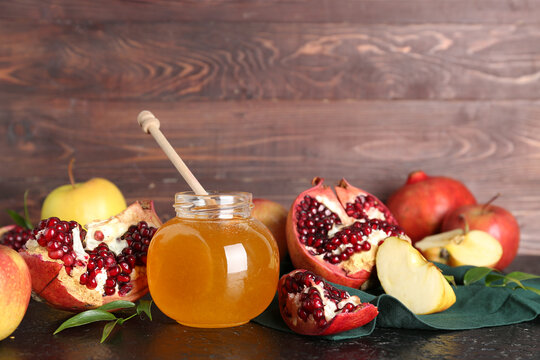 Jar of honey, pomegranate and apples for Rosh Hashanah celebration (Jewish New Year) on black table