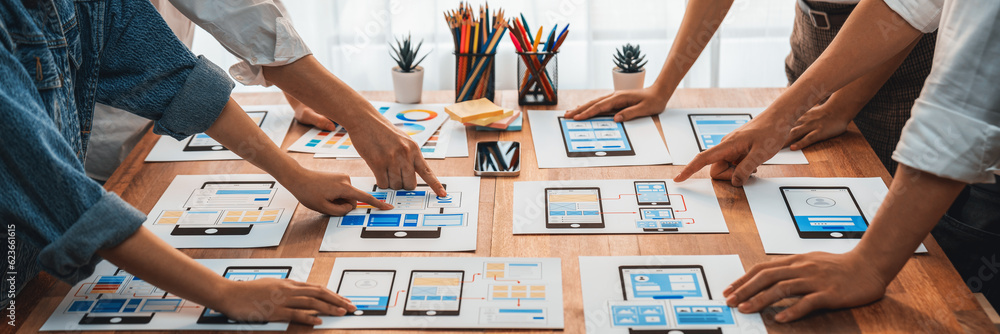 Poster Panorama shot of front-end developer team brainstorming UI and UX designs for mobile app on paper wireframe interface. User interface development team planning for user-friendly UI design. Scrutinize