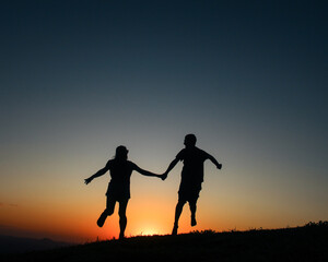 Fototapeta na wymiar Silhueta de casal de mãos dadas caminhando no pôr do sol