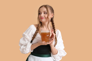 Beautiful Octoberfest waitress with beer on beige background