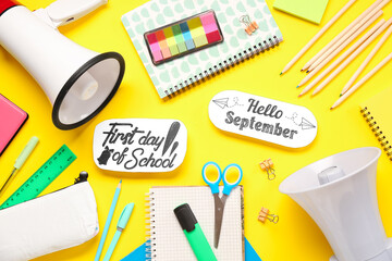 Stationery, megaphone, sheets with text HELLO SEPTEMBER and FIRST DAY OF SCHOOL on yellow background