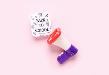Megaphone and sheet with text BACK TO SCHOOL on pink background
