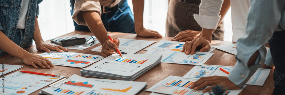 Leinwandbilder Analyst team utilizing BI Fintech to analyze and pointing at financial dashboard paper office. Businesspeople examining report paper on table for business insight. Panorama shot. Scrutinize