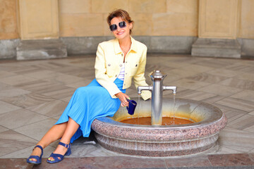 Woman drink a water from hot mineral spring in Karlovy Vary in special mug