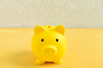 Piggy bank on yellow table near wall
