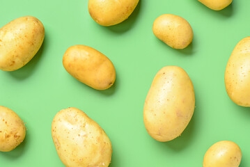 Raw potatoes on green background