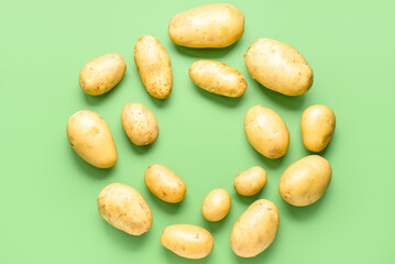 Frame made of raw potatoes on green background