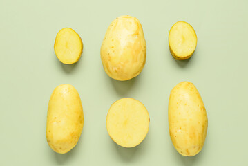 Raw potatoes on green background