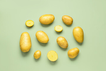 Raw potatoes on green background