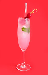 Glass of tasty cocktail with maraschino cherries on red background