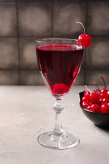 Glass of tasty cocktail with maraschino cherries on table