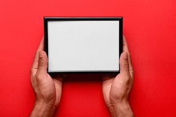 Man holding blank photo frame on red background