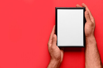 Man holding blank photo frame on red background