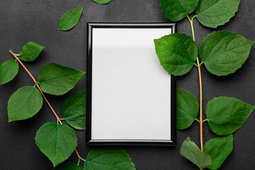 Blank photo frame and leaves on black background