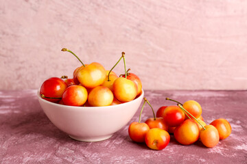 Bowl with sweet yellow cherries on purple background