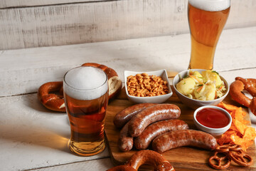 Glasses of cold beer and board with different snacks on light wooden background. Oktoberfest celebration