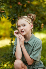 Beautiful girl in the garden. Happy girl in the apple orchard. Apple trees. Childhood. Children's fashion and style.