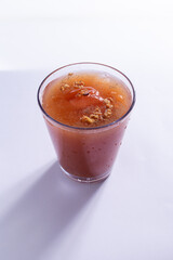 Suco de tomate servido em copo de vidro em fundo branco