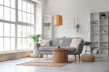 Interior of light living room with grey sofa, wooden coffee table and big window