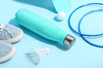 Bottle of water, shoes and sports equipment on color background