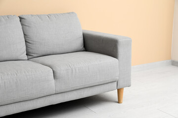 Cozy grey sofa near beige wall