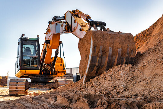 Crawler excavator with bucket pulled forward at a construction site. Close-up of a powerful excavator. Rental of construction equipment. Earthworks contractor.