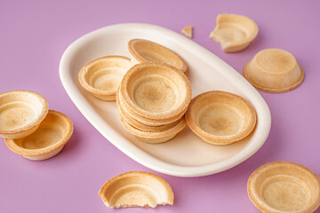 Bowl with homemade tartlets on lilac background
