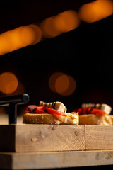 sandwich on wooden plate with out-of-focus lights in the background