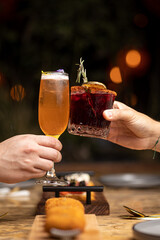 toasting in a restaurant with two cocktails, at a table with dishes