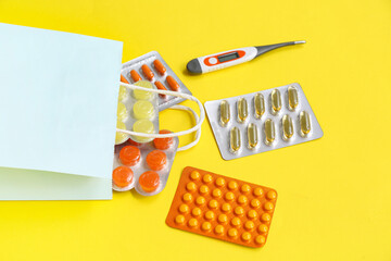 Shopping bag with different medicines on yellow background