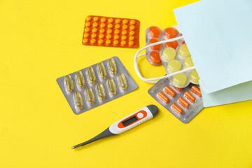 Shopping bag with different medicines on yellow background