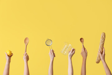 Female hands with baking utensils and baguette on yellow background